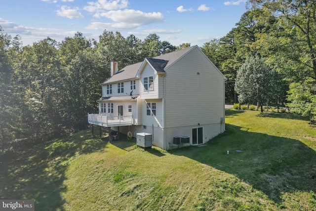 view of side of property featuring a wooden deck, a yard, and central AC unit