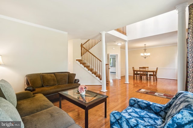 living room featuring hardwood / wood-style floors, a notable chandelier, crown molding, and decorative columns