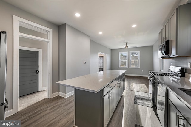 kitchen with gray cabinetry, stainless steel appliances, a center island, and dark hardwood / wood-style floors