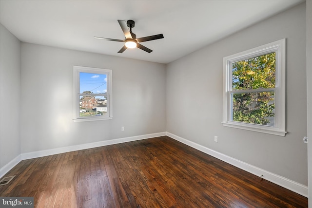 spare room featuring a wealth of natural light, dark hardwood / wood-style floors, and ceiling fan