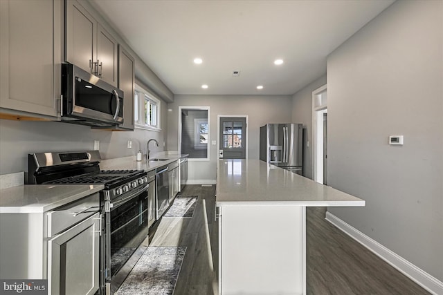 kitchen featuring appliances with stainless steel finishes, sink, dark hardwood / wood-style flooring, a center island, and gray cabinets