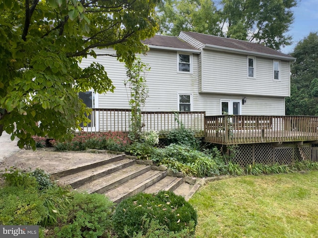 back of property with a wooden deck and a lawn