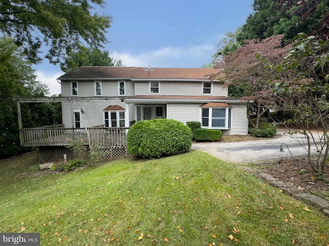 back of property featuring a wooden deck and a yard