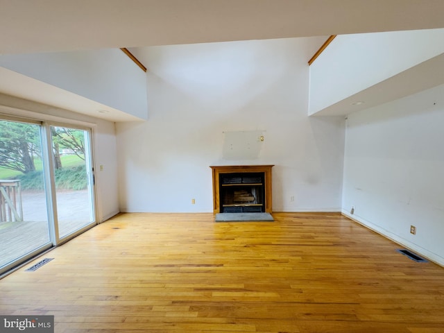 unfurnished living room with light hardwood / wood-style floors and a high ceiling