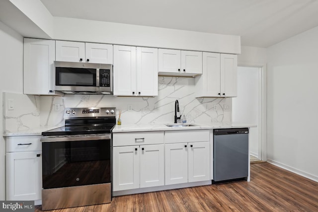 kitchen with white cabinets, tasteful backsplash, dark wood-type flooring, sink, and stainless steel appliances