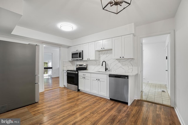 kitchen featuring sink, backsplash, stainless steel appliances, white cabinets, and dark hardwood / wood-style floors