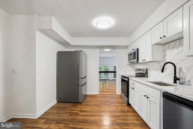 kitchen with dark hardwood / wood-style floors, sink, light stone countertops, white cabinets, and appliances with stainless steel finishes