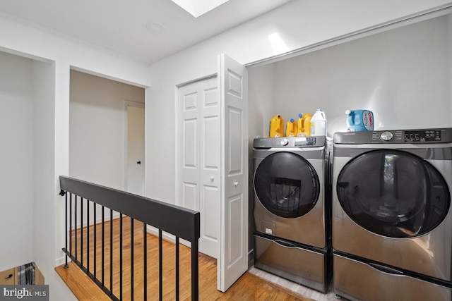 washroom with a skylight, wood-type flooring, and washer and clothes dryer