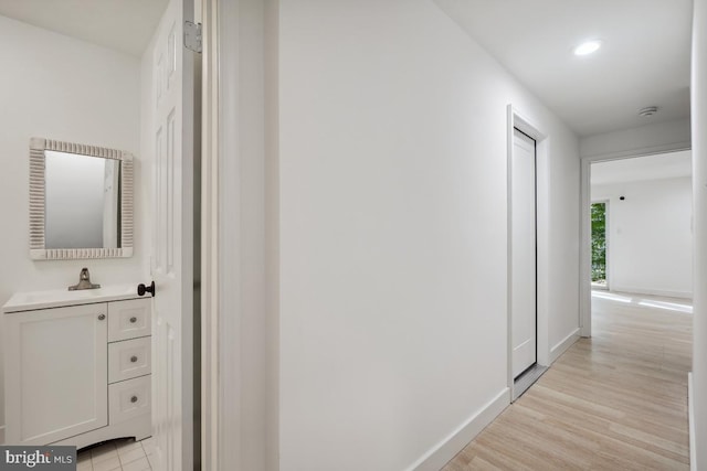 hall with sink and light hardwood / wood-style flooring