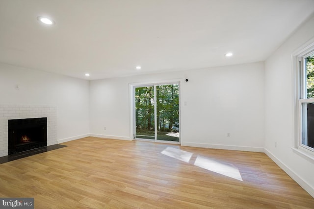 unfurnished living room with a fireplace and light wood-type flooring