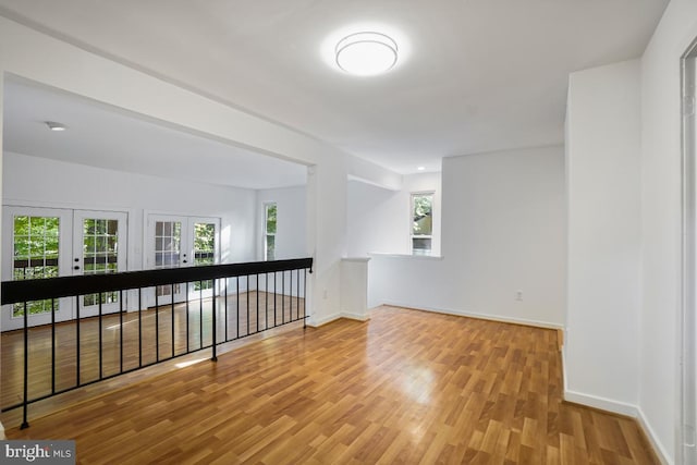 empty room featuring light hardwood / wood-style floors, french doors, and a healthy amount of sunlight