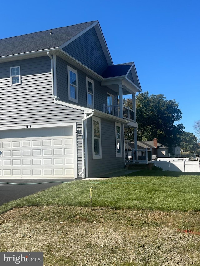 view of front facade with a front yard, a balcony, and a garage