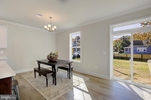 dining room with light hardwood / wood-style floors, crown molding, and a chandelier