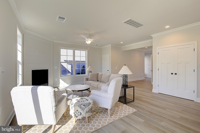 living room featuring light hardwood / wood-style flooring, ornamental molding, a fireplace, and ceiling fan