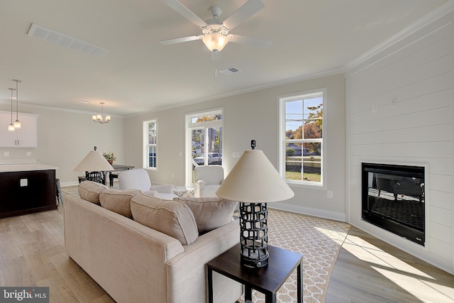 living room featuring a large fireplace, ornamental molding, and light hardwood / wood-style floors