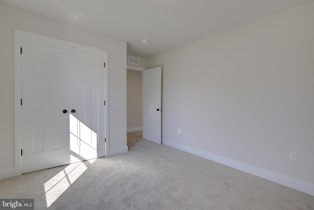 unfurnished bedroom featuring light carpet and a closet