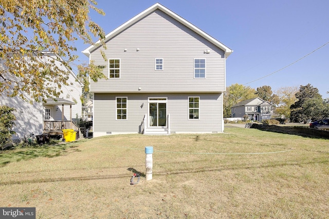 rear view of property featuring a wooden deck and a lawn