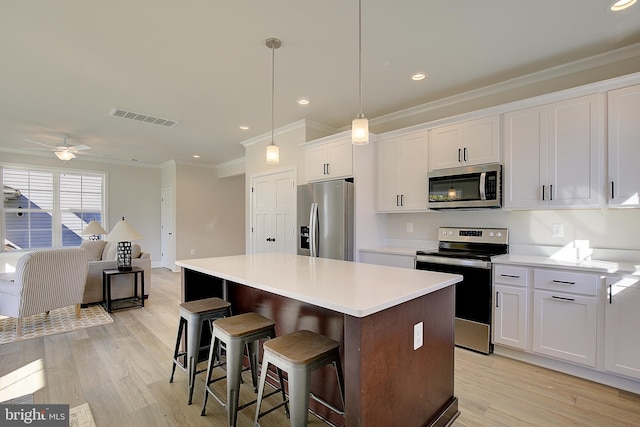 kitchen with appliances with stainless steel finishes, white cabinetry, and a center island