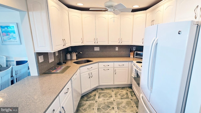 kitchen featuring decorative backsplash, white appliances, ceiling fan, sink, and white cabinets