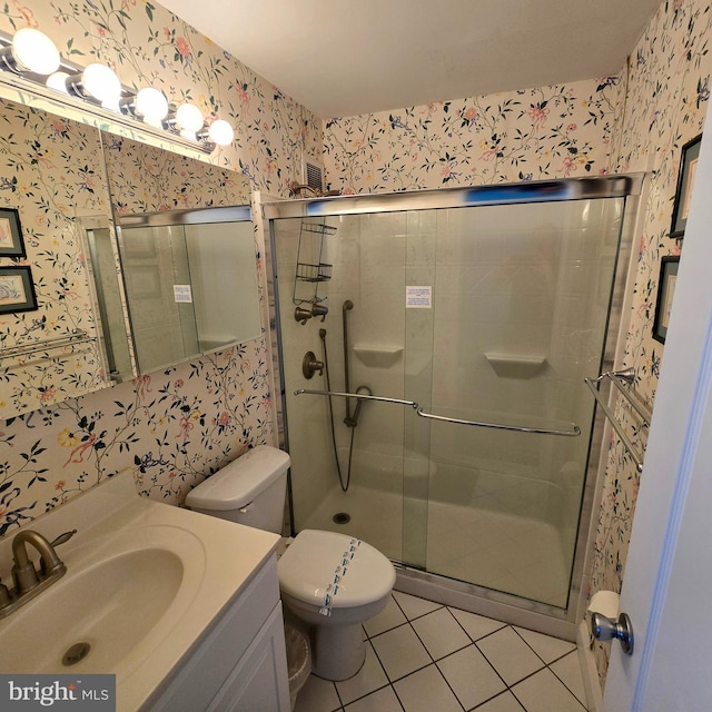 bathroom featuring tile patterned flooring, vanity, a shower with shower door, and toilet