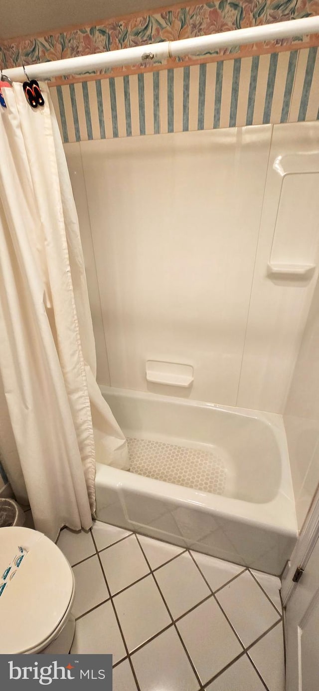 bathroom featuring toilet, tile patterned floors, and shower / bath combo with shower curtain