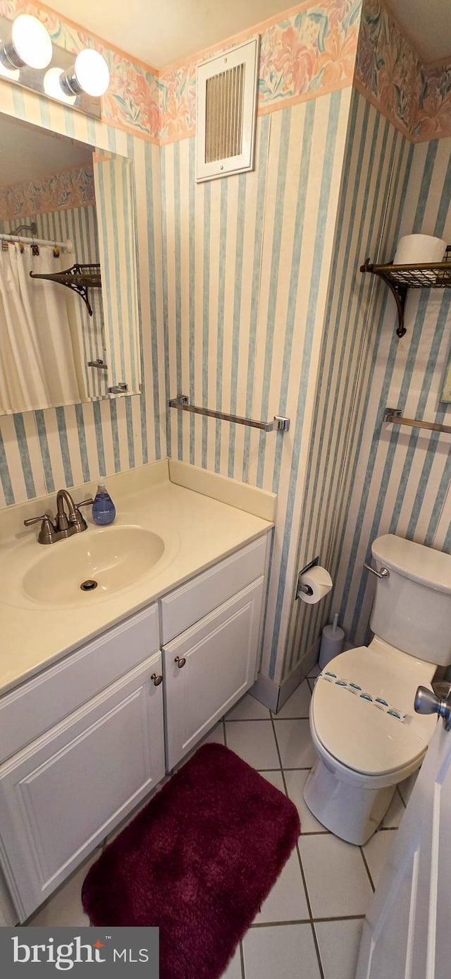 bathroom with tile patterned flooring, vanity, and toilet