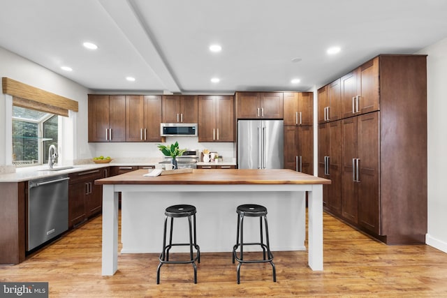 kitchen featuring appliances with stainless steel finishes, a center island, light wood-style floors, and a breakfast bar area