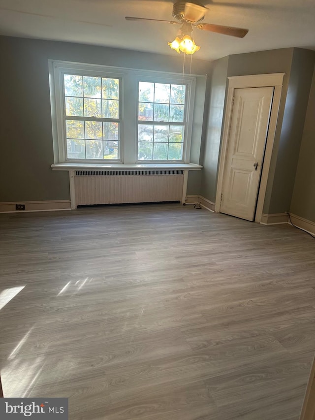 spare room featuring light hardwood / wood-style floors, radiator, and ceiling fan