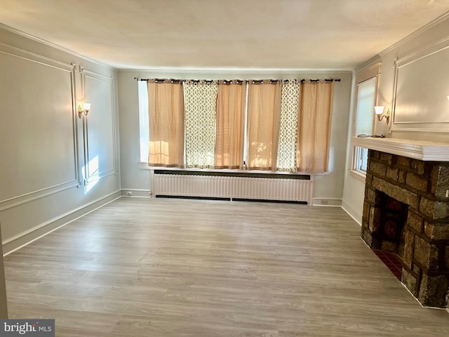 unfurnished living room with light hardwood / wood-style floors, crown molding, and radiator heating unit