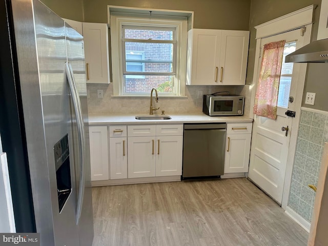 kitchen featuring light hardwood / wood-style flooring, stainless steel appliances, sink, white cabinets, and tasteful backsplash