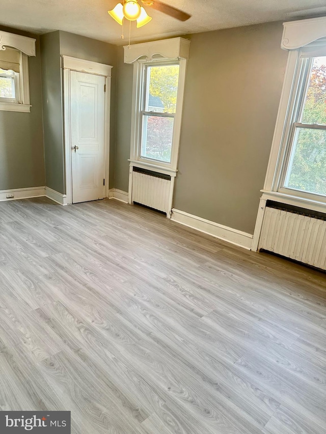 spare room featuring plenty of natural light, light wood-type flooring, and radiator