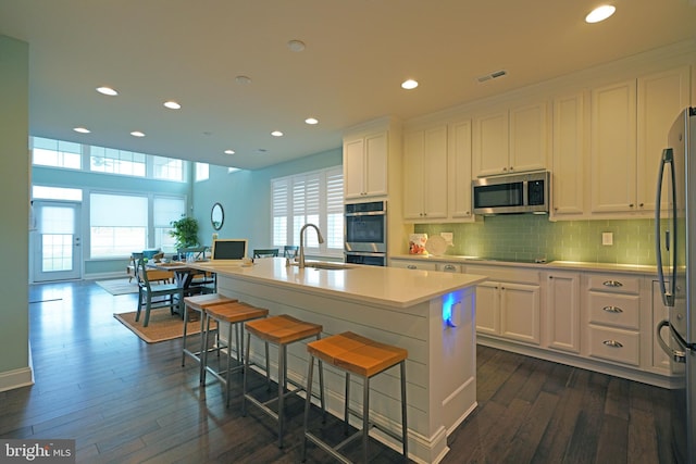 kitchen with stainless steel appliances, white cabinetry, sink, and dark hardwood / wood-style flooring