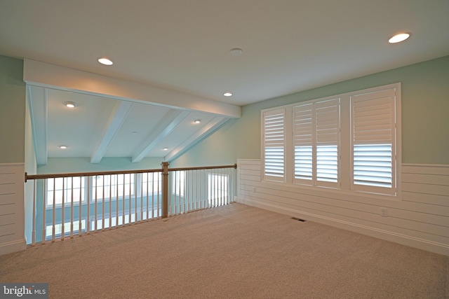 empty room with carpet flooring and vaulted ceiling with beams