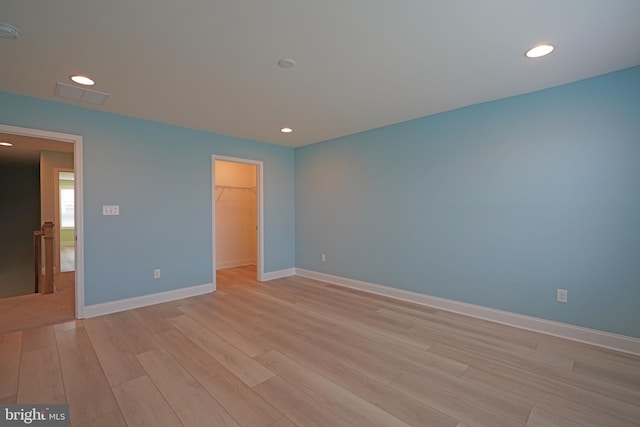 unfurnished bedroom with a closet, light wood-type flooring, and a walk in closet