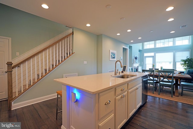 kitchen with an island with sink, dark hardwood / wood-style floors, sink, and stainless steel dishwasher