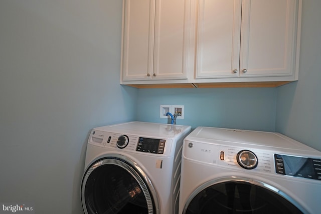 washroom featuring washing machine and clothes dryer and cabinets