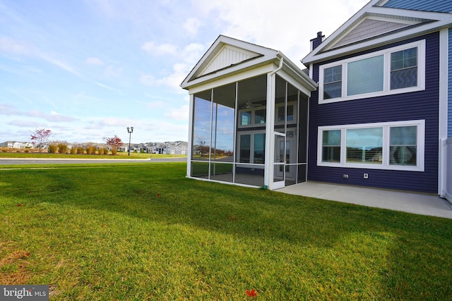 rear view of property with a patio, ceiling fan, a sunroom, and a yard