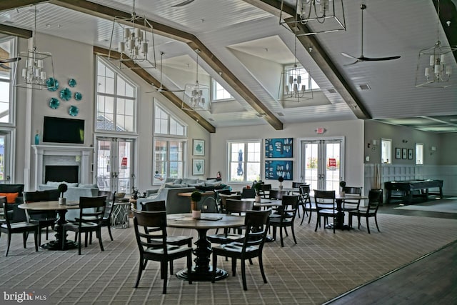 carpeted dining area with a towering ceiling, ceiling fan, and french doors