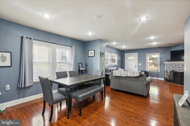 dining area featuring dark wood-type flooring and a tile fireplace