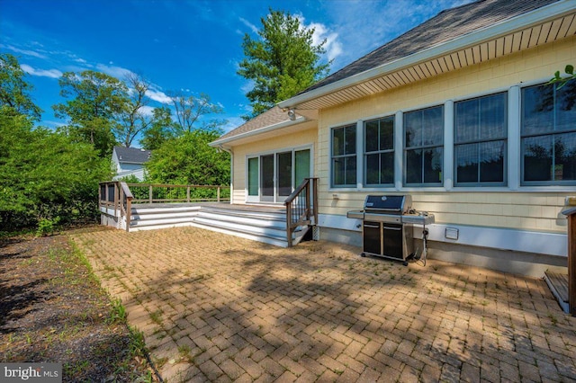 exterior space featuring a deck, a patio, and roof with shingles