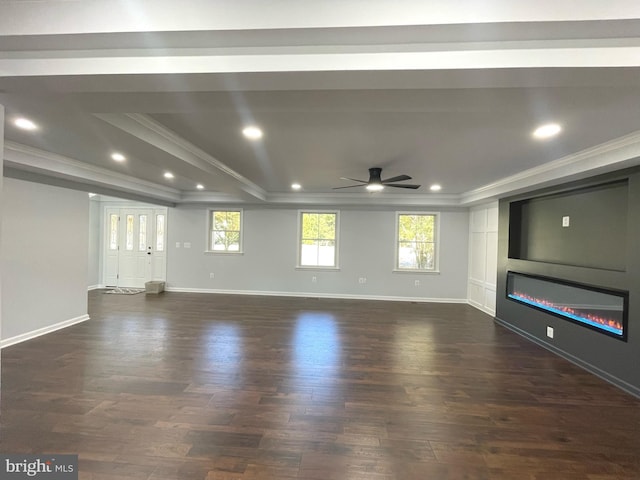 unfurnished living room featuring ornamental molding, dark wood-type flooring, ceiling fan, a tray ceiling, and a glass covered fireplace