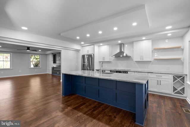 kitchen featuring stainless steel refrigerator with ice dispenser, white cabinetry, wall chimney exhaust hood, and sink