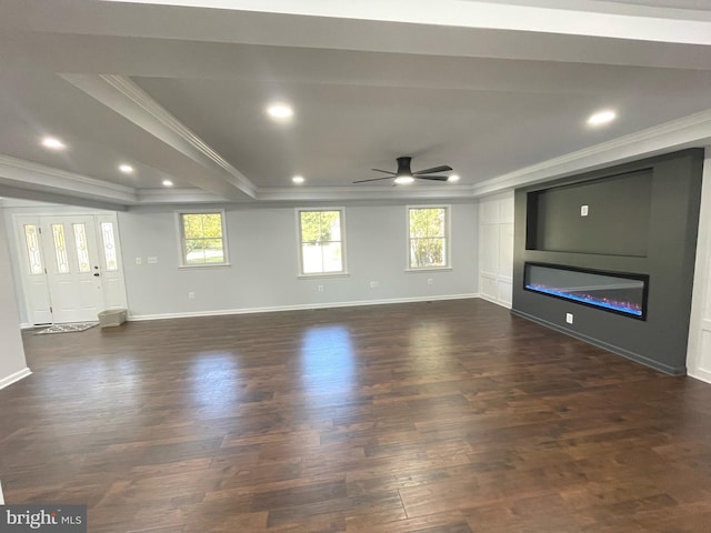 unfurnished living room with ornamental molding, dark wood-style floors, a ceiling fan, a raised ceiling, and a glass covered fireplace