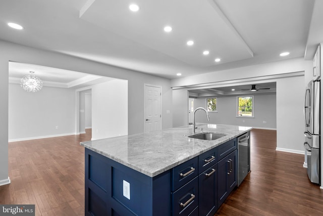 kitchen featuring appliances with stainless steel finishes, light stone counters, ceiling fan with notable chandelier, sink, and an island with sink