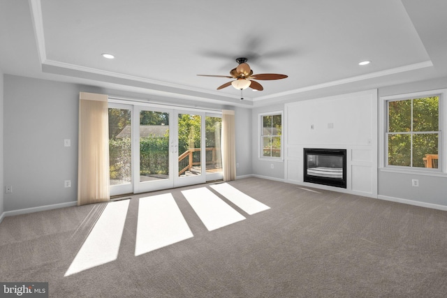 unfurnished living room featuring light carpet, a raised ceiling, ceiling fan, and crown molding