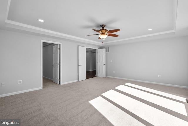 unfurnished bedroom with ceiling fan, a raised ceiling, ornamental molding, and light carpet