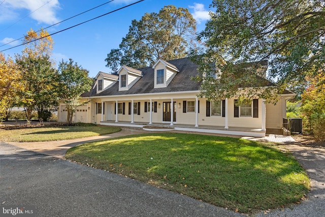 new england style home featuring cooling unit, a front lawn, covered porch, and a garage