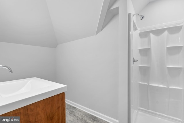 bathroom featuring hardwood / wood-style flooring, vanity, walk in shower, and vaulted ceiling