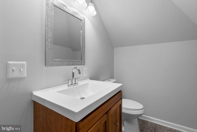 bathroom with vanity, toilet, and lofted ceiling