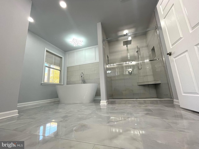 bathroom with a stall shower, marble finish floor, baseboards, and a freestanding bath